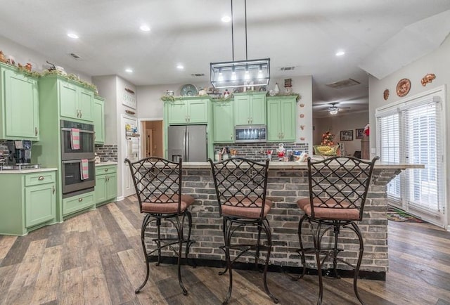 kitchen with stainless steel appliances, a kitchen bar, and green cabinets