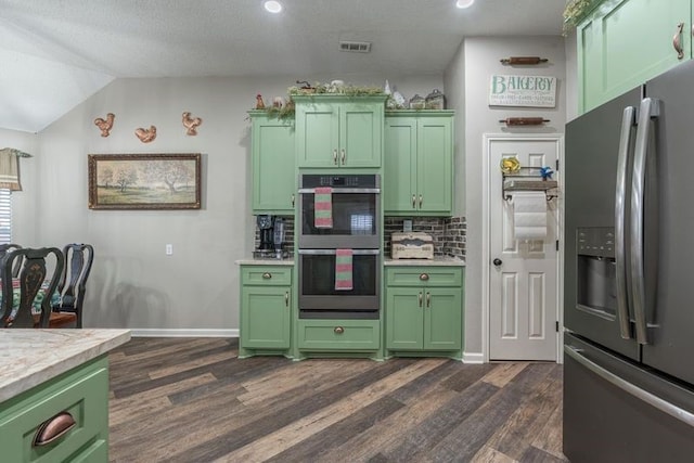 kitchen with dark wood-type flooring, vaulted ceiling, decorative backsplash, appliances with stainless steel finishes, and green cabinetry