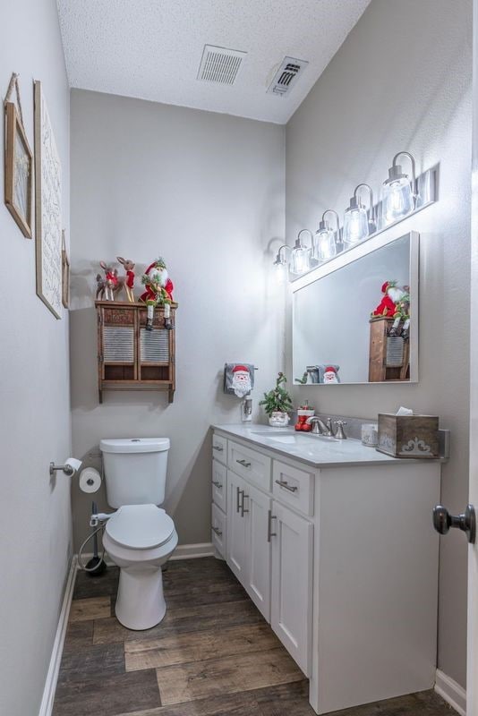 bathroom with toilet, vanity, a textured ceiling, and hardwood / wood-style flooring