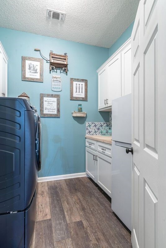 laundry area featuring washing machine and dryer, dark wood-type flooring, cabinets, and a textured ceiling