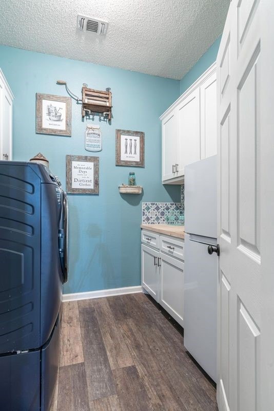 laundry area featuring cabinets, washer and dryer, dark hardwood / wood-style floors, and a textured ceiling