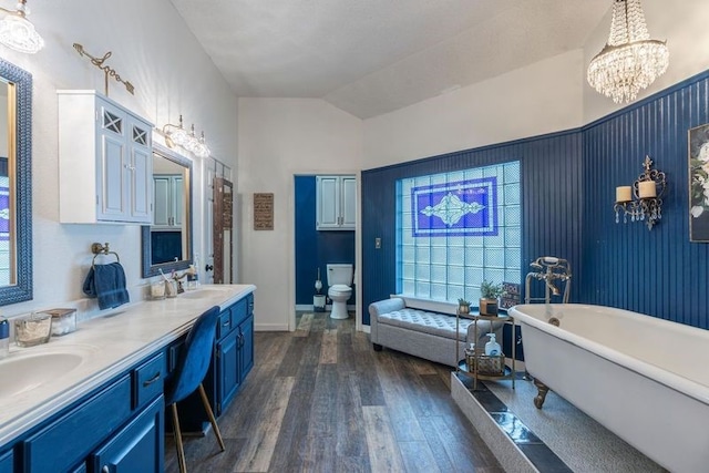 bathroom with a washtub, vanity, wood-type flooring, toilet, and lofted ceiling