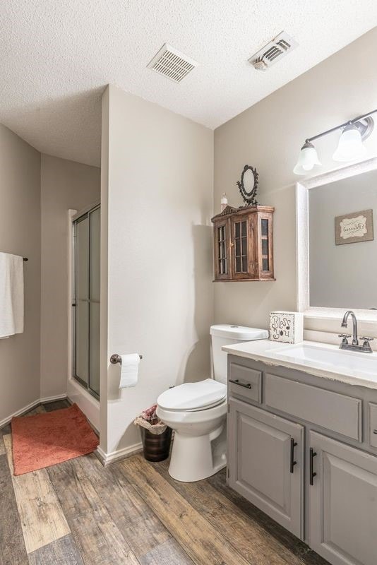 bathroom featuring hardwood / wood-style flooring, vanity, an enclosed shower, and a textured ceiling