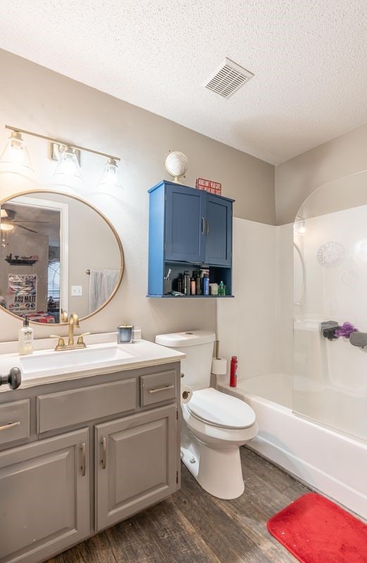 full bathroom with toilet, bathtub / shower combination, a textured ceiling, vanity, and hardwood / wood-style flooring