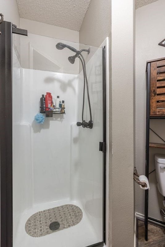 bathroom with hardwood / wood-style floors, a textured ceiling, toilet, and walk in shower