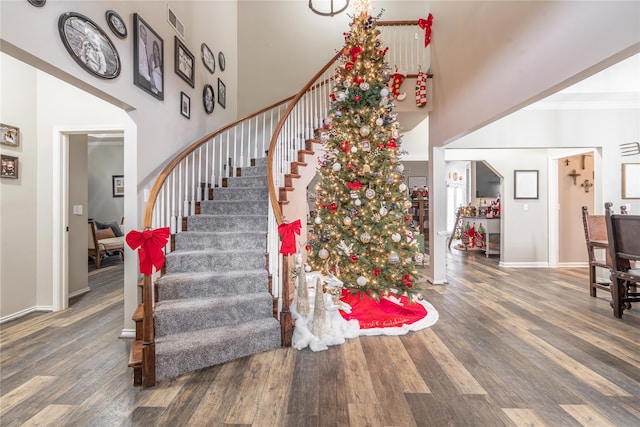 stairs featuring hardwood / wood-style floors, a towering ceiling, and crown molding