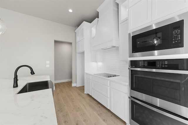 kitchen with white cabinetry, sink, custom range hood, and built in microwave