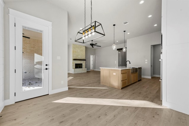 kitchen featuring ceiling fan, light hardwood / wood-style flooring, pendant lighting, a kitchen island with sink, and light brown cabinetry