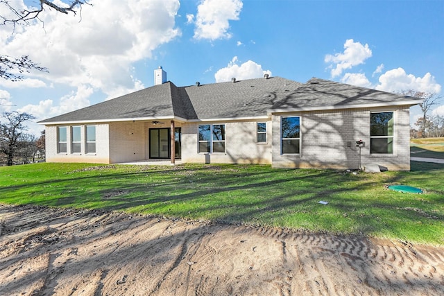 back of property with ceiling fan and a yard