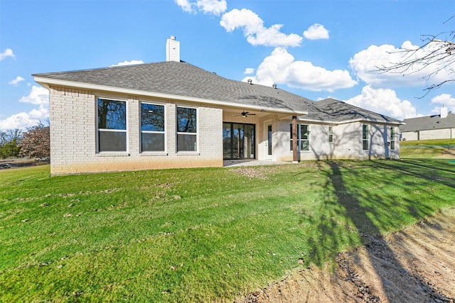 back of property with ceiling fan and a yard