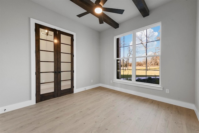 empty room featuring beam ceiling, a wealth of natural light, ceiling fan, and light wood-type flooring