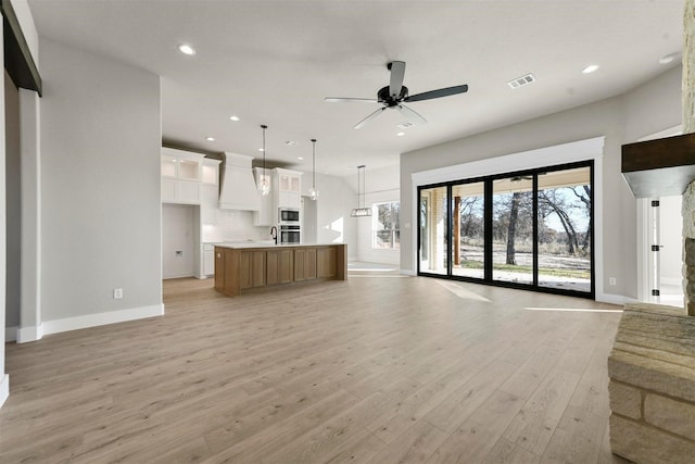 unfurnished living room featuring ceiling fan and light hardwood / wood-style floors