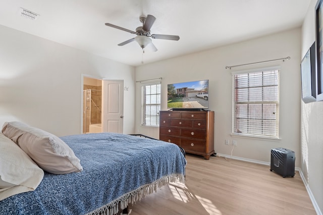 bedroom with multiple windows, ensuite bathroom, light hardwood / wood-style flooring, and ceiling fan