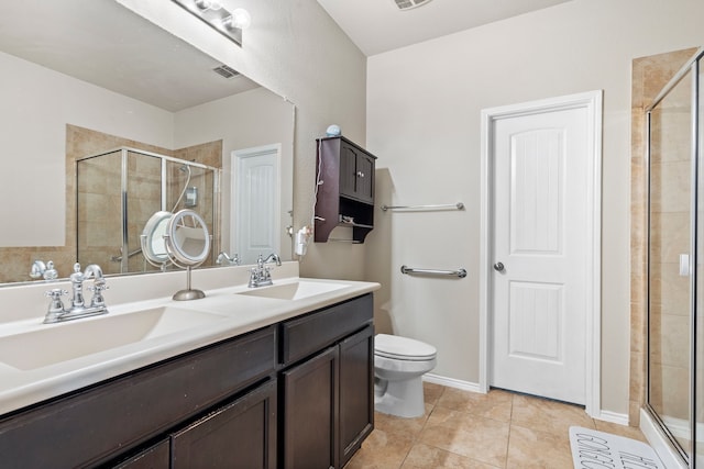 bathroom with tile patterned floors, vanity, a shower with shower door, and toilet