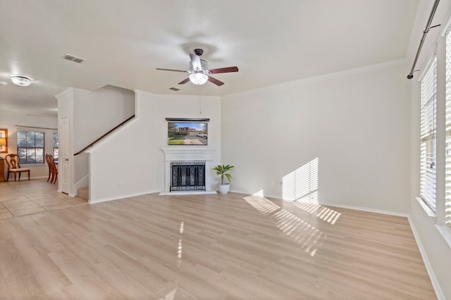 unfurnished living room with crown molding, ceiling fan, and light wood-type flooring