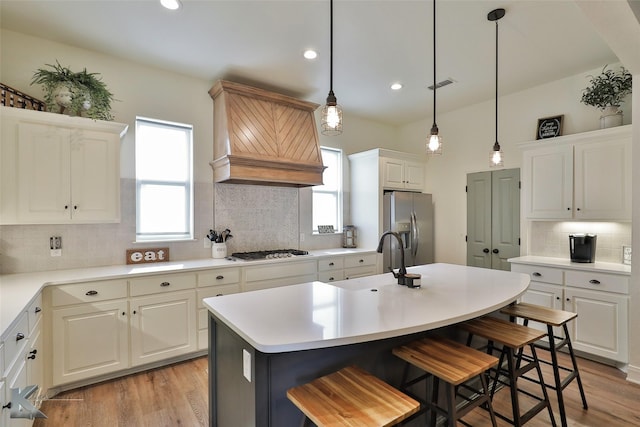 kitchen with stainless steel appliances, white cabinetry, a kitchen island with sink, and a kitchen breakfast bar