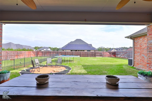 view of yard featuring ceiling fan, central AC unit, and a trampoline