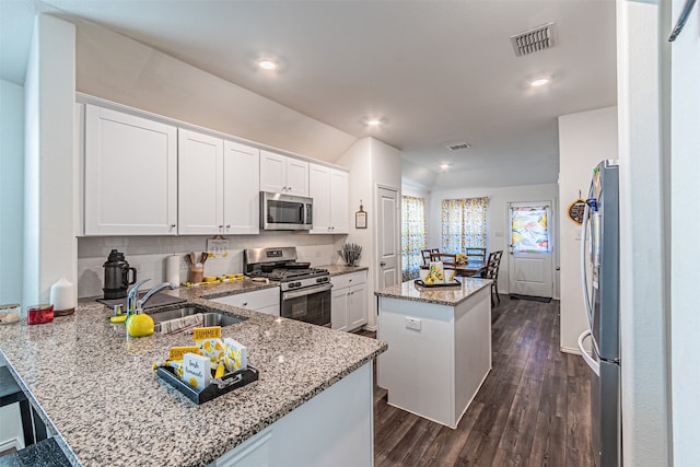 kitchen with white cabinetry, sink, stainless steel appliances, dark hardwood / wood-style floors, and kitchen peninsula