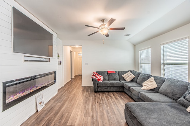 living room featuring a fireplace, hardwood / wood-style floors, vaulted ceiling, and ceiling fan