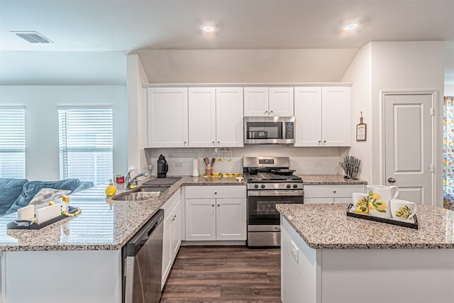 kitchen featuring white cabinets, backsplash, stainless steel appliances, and dark wood-type flooring