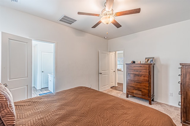 bedroom featuring ceiling fan, light colored carpet, and ensuite bathroom