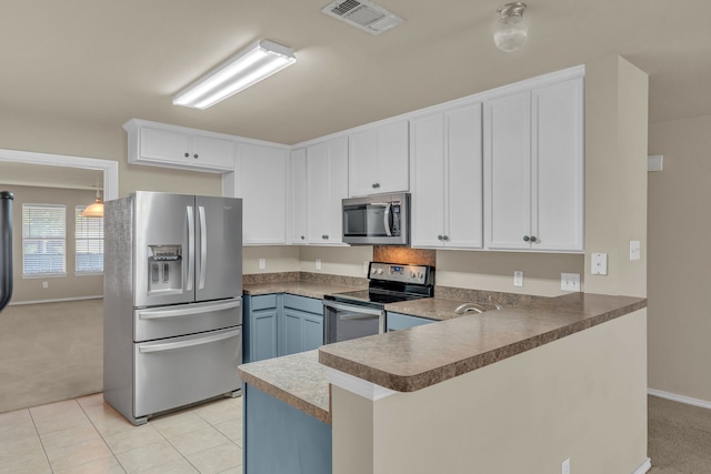 kitchen with kitchen peninsula, light carpet, stainless steel appliances, and white cabinetry