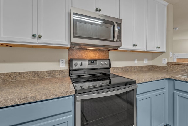 kitchen with white cabinetry, blue cabinets, and appliances with stainless steel finishes