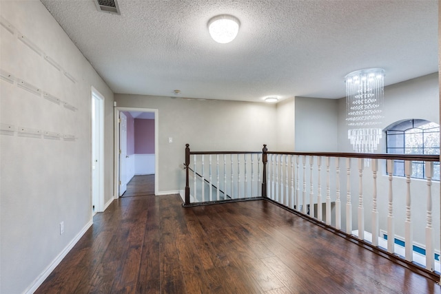 empty room with french doors, dark hardwood / wood-style flooring, a textured ceiling, and a brick fireplace