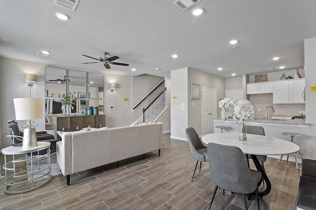 living room featuring hardwood / wood-style flooring, ceiling fan, sink, and a textured ceiling