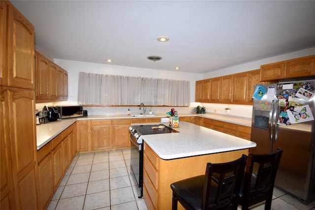 kitchen featuring appliances with stainless steel finishes, sink, a kitchen bar, a center island, and light tile patterned floors