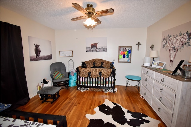 bedroom featuring ceiling fan, light hardwood / wood-style floors, and a textured ceiling