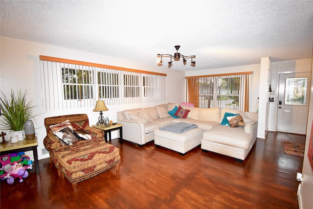 living room featuring dark wood-type flooring, a chandelier, and a textured ceiling