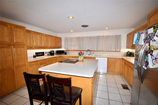 kitchen featuring light tile patterned flooring, appliances with stainless steel finishes, a kitchen island, and a breakfast bar area