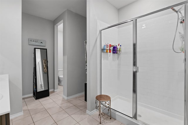 bathroom with tile patterned floors, a shower with shower door, and toilet