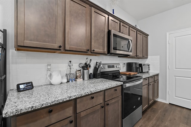 kitchen featuring light stone countertops, dark hardwood / wood-style floors, backsplash, dark brown cabinets, and appliances with stainless steel finishes