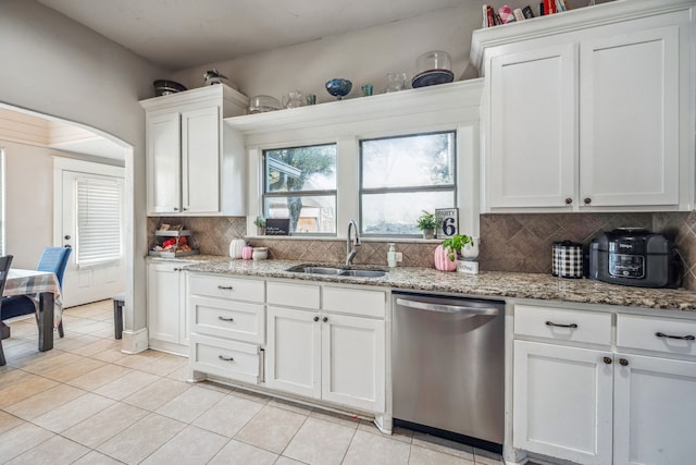 kitchen featuring light stone counters, decorative backsplash, white cabinetry, a sink, and dishwasher