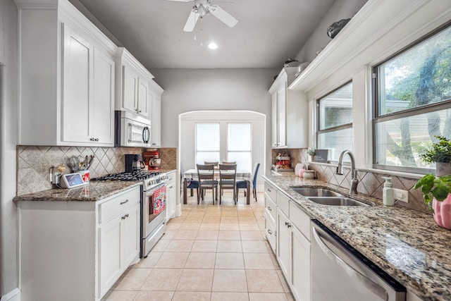 kitchen featuring stainless steel appliances, stone countertops, a sink, and white cabinets