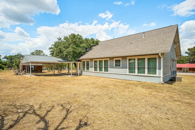 back of property featuring a carport, a lawn, and roof with shingles