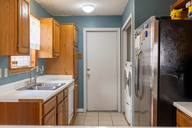 kitchen with sink, stainless steel fridge with ice dispenser, independent washer and dryer, a textured ceiling, and light tile patterned floors