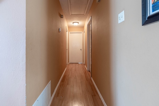 hall featuring light hardwood / wood-style flooring and a textured ceiling