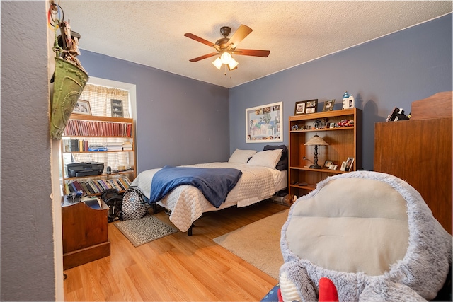 bedroom featuring ceiling fan, wood-type flooring, and a textured ceiling