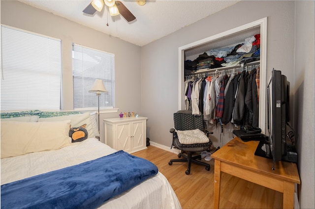 bedroom with a textured ceiling, light hardwood / wood-style flooring, a closet, and ceiling fan