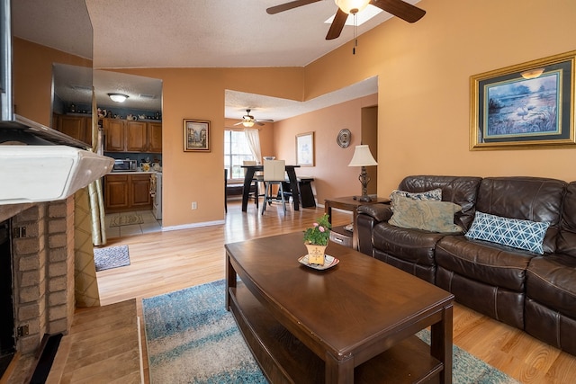 living room featuring ceiling fan, lofted ceiling, and light wood-type flooring