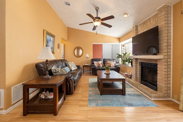 living room featuring a textured ceiling, light hardwood / wood-style flooring, ceiling fan, and lofted ceiling