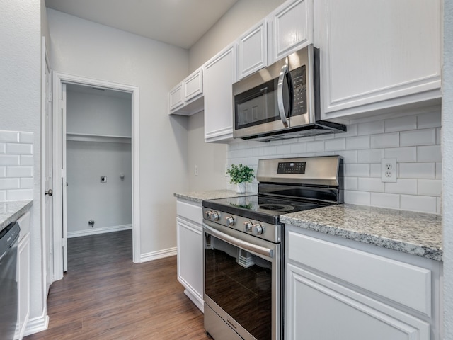 kitchen with appliances with stainless steel finishes, dark hardwood / wood-style floors, white cabinetry, and tasteful backsplash