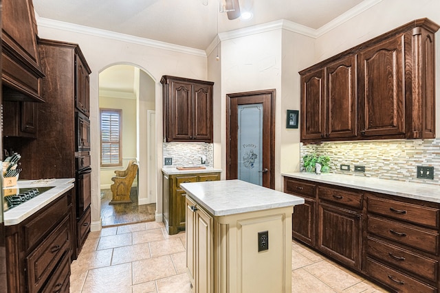 kitchen featuring a center island, tasteful backsplash, ornamental molding, black appliances, and cream cabinetry