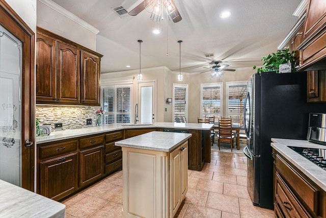 kitchen featuring pendant lighting, sink, decorative backsplash, a center island, and ceiling fan