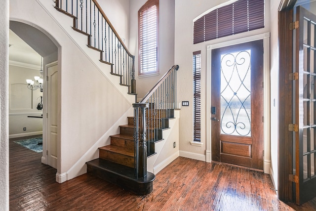 foyer entrance featuring dark hardwood / wood-style floors, ornamental molding, and a notable chandelier