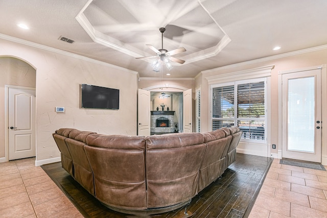 living room featuring crown molding, ceiling fan, a raised ceiling, and tile patterned flooring