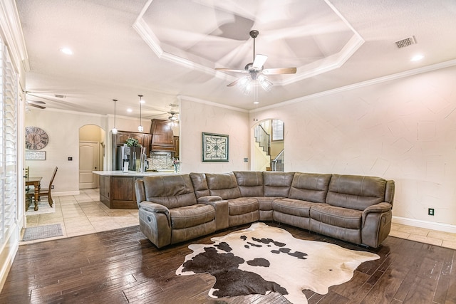 living room featuring crown molding, ceiling fan, a raised ceiling, and light hardwood / wood-style floors